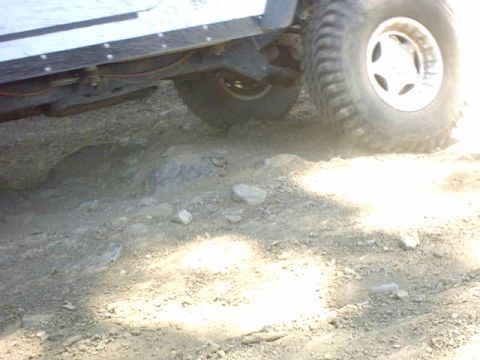 1995 Ford Bronco - Undercarriage and tire of an off-road vehicle navigating a rocky trail.