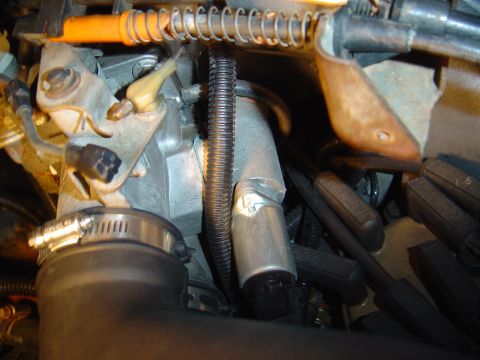 1986 Ford Bronco - Close-up inside an engine bay showing a cast-aluminum bracket, black-jacketed spark plug wires with heat boots, and a corrugated split-loom…