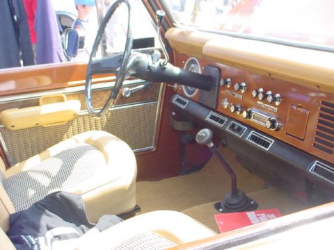 1979 Ford Bronco - The interior of a 1979 Ford Bronco features a woodgrain dashboard, plaid seat upholstery, and a floor-mounted shifter.