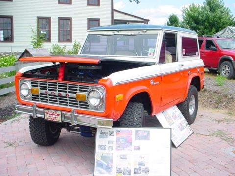 1979 Ford Bronco - Orange and white 1979 Ford Bronco on display, hood raised to show engine compartment.