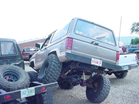 1979 Ford Bronco - This lifted 1979 Ford Bronco features oversized tires and a personalized 'KRAWLN' license plate, seen here with other vehicles.