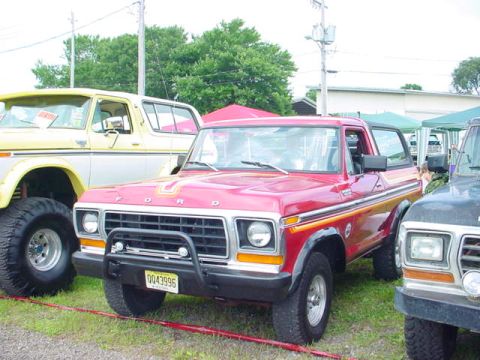 1979 Ford Bronco - Red 1978 Ford Bronco with distinctive side stripes, parked outdoors at an event with other vehicles.