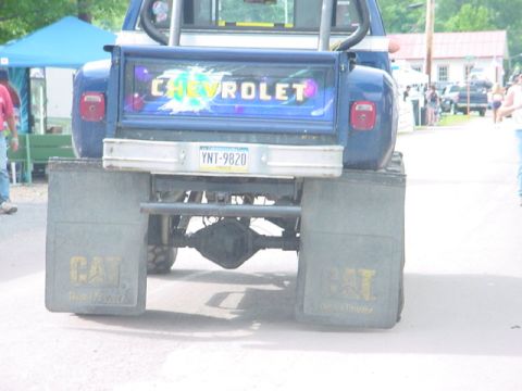 1979 Ford Bronco - This blue Chevrolet pickup truck features large mud flaps with CAT branding and a colorful "CHEVROLET" decal on the tailgate.