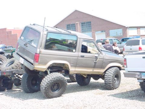 1979 Ford Bronco - This lifted SUV is parked next to other vehicles in what appears to be a parking lot or junkyard.