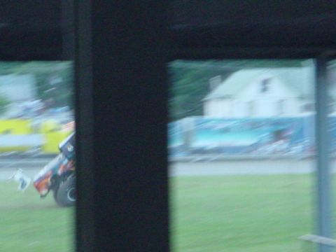 1979 Ford Bronco - A monster truck is shown in profile, with a blurred background of a building and a grassy field.