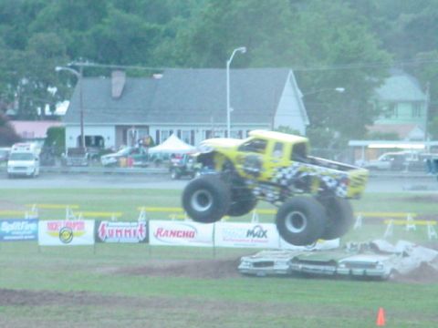 1979 Ford Bronco - A yellow monster truck soars through the air, crushing cars below during an event.