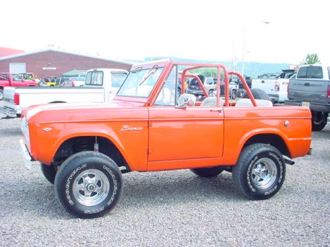 1979 Ford Bronco - This classic orange Ford Bronco is shown from the side, with other vehicles visible in the background.