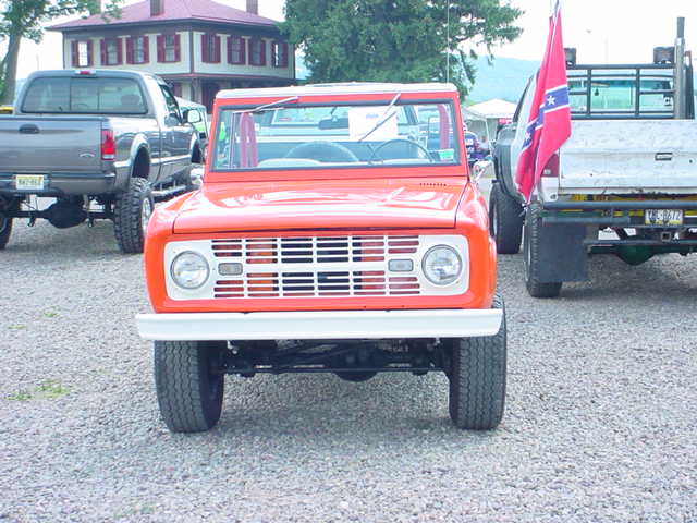Orange SUV with a white grille and round headlights, parked on gravel