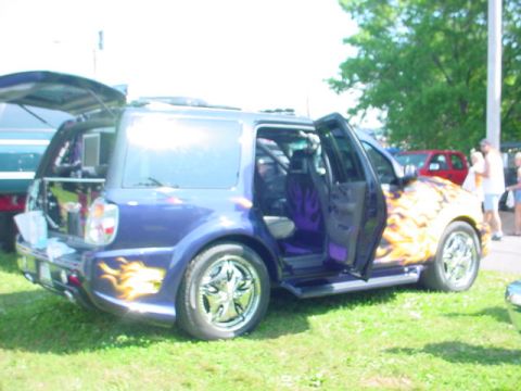 1979 Ford Bronco - This customized SUV features flame graphics and a vibrant interior, with another vehicle visible in the background.