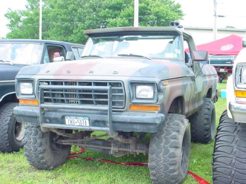 1979 Ford Bronco - This 1979 Ford Bronco, seen from the front, features a camouflage paint scheme and aggressive off-road tires.