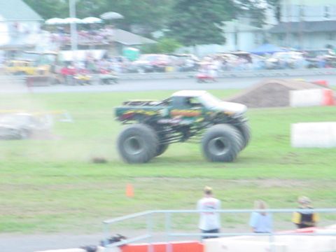 1979 Ford Bronco - A monster truck with oversized tires is seen in a grassy field, possibly at an event.