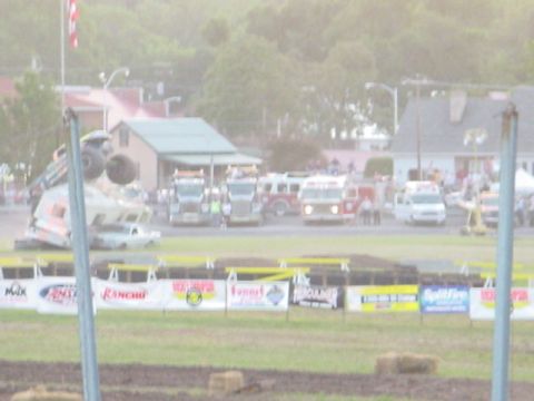 1979 Ford Bronco - A monster truck is overturned at an event, with several other vehicles and spectators in the background.