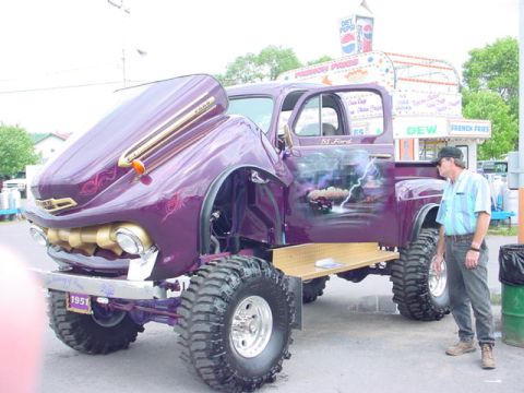 1979 Ford Bronco - A man stands by a heavily modified 1951 Ford pickup truck with custom paint and large off-road tires.