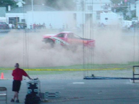 1979 Ford Bronco - A red pickup truck performs a burnout, creating a large cloud of dust.