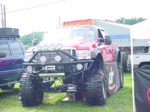 1979 Ford Bronco - Modified red Ford F-series truck on display with custom off-road accessories.