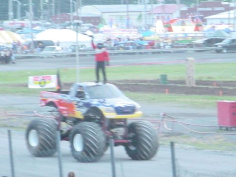 1979 Ford Bronco - A person stands atop a monster truck during an event.