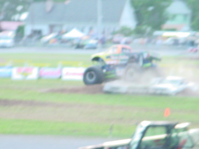 Monster truck driving over crushed cars on a dirt track
