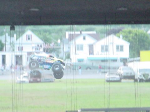 1979 Ford Bronco - A monster truck performs a jump over a pile of cars during an event.