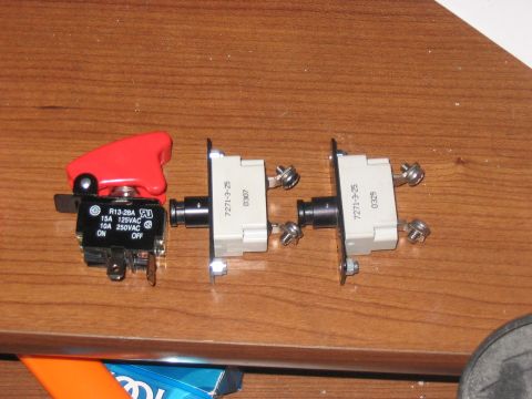 1988 Ford Bronco - Three electrical switches, including a red toggle and two white breakers, are laid out on a wooden surface.