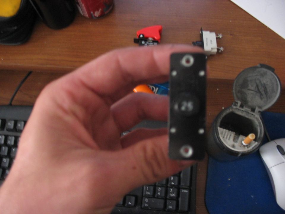 Black fuse with "25" visible, held in a hand over a keyboard