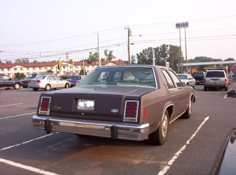 1991 Ford Crown Victoria LTD - Rear view of a brown sedan parked in a lot with other vehicles visible.