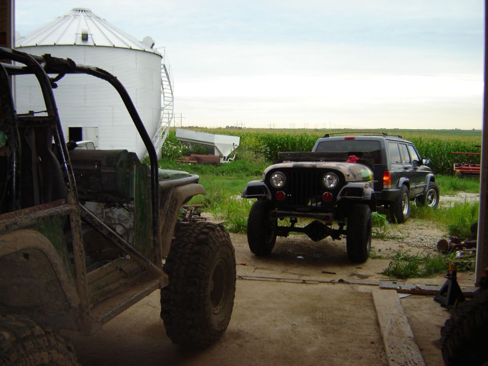 Front view of a modified Jeep with a dark SUV behind it
