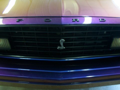 1978 Ford Mustang II - The grille features the iconic snake emblem and 'FORD' lettering on a purple-painted hood.