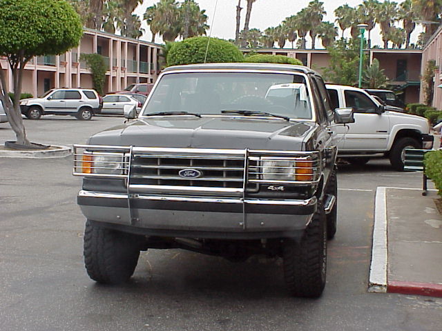 Front view of a black lifted Ford Bronco with chrome brush guard and 4x4 badge in a motel parking lot