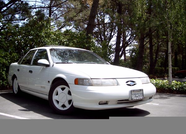 White 1992 Ford Taurus parked outside with trees in the background. License plate reads 278S510 JESUS