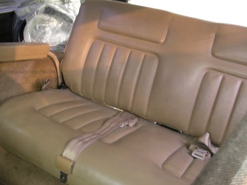 1984 Chevrolet Blazer - Interior view of tan vinyl bench seat with seatbelts and carpeted side panel.