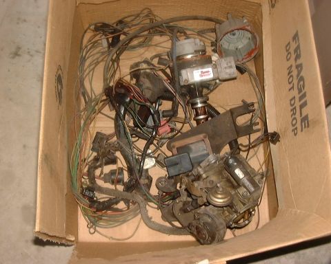 1985 Ford F-150 - A cardboard box contains a tangled mess of engine wiring, a distributor, and a carburetor.