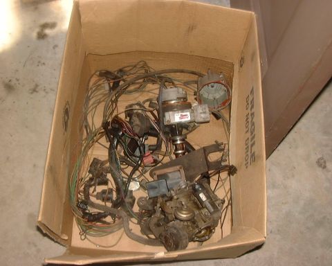 1985 Ford F-150 - Engine components and wiring are piled inside a cardboard box.