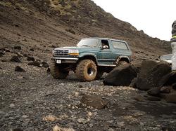 1984 Ford Bronco - This green Ford Bronco, likely a 1987 model, navigates a challenging rocky landscape.