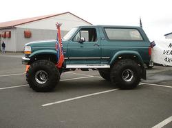 1984 Ford Bronco - Modified teal Ford Bronco with large tires and a Confederate flag, likely a 1992 model.