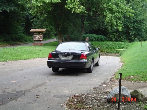 1999 Ford Crown Victoria - Rear view of a black 1999 Ford Crown Victoria parked near a recreation area sign.