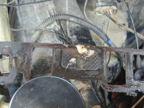 1988 Ford Bronco - Close-up of a damaged engine gasket with associated wiring, showing signs of wear and tear.