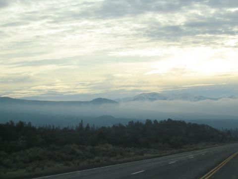 1989 Ford Bronco - A highway vista unfolds with distant mountains shrouded in mist and clouds overhead.
