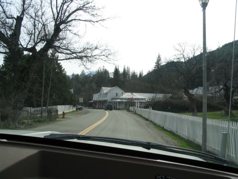 1989 Ford Bronco - A view down a road lined with a white picket fence, leading to a cluster of buildings in a rural setting.