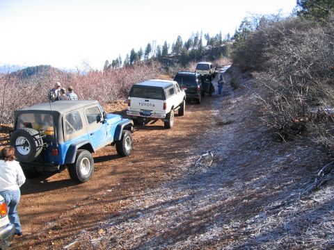 1989 Ford Bronco - A convoy of off-road vehicles travels down a dusty, frost-covered mountain road.
