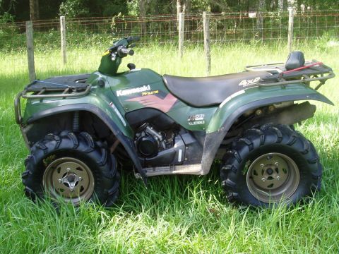 1993 Ford Bronco - Green Kawasaki Prairie 300 ATV with aggressive tires sits in a grassy field.