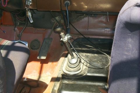 1978 Ford Bronco - The interior of a vehicle shows the floor pedals and shifter mechanism.