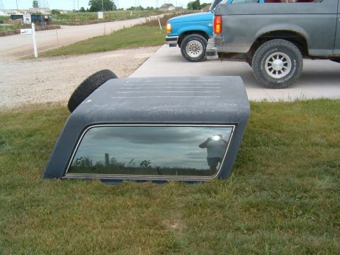 1987 Ford Bronco - Ford Bronco hardtop removed from vehicle, parked next to two trucks.