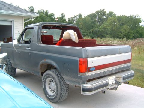 1987 Ford Bronco - Rear view of a dark gray 1987 Ford Bronco, its red interior and removable top.