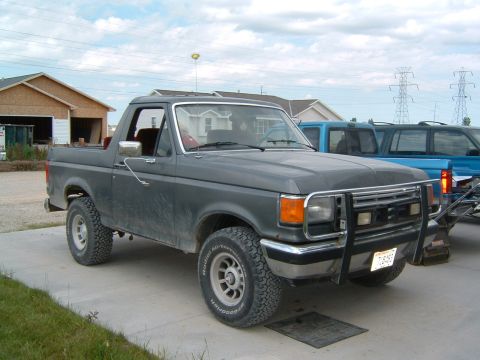 1987 Ford Bronco - This 1987 Ford Bronco is parked in front of two blue trucks on a cloudy day.