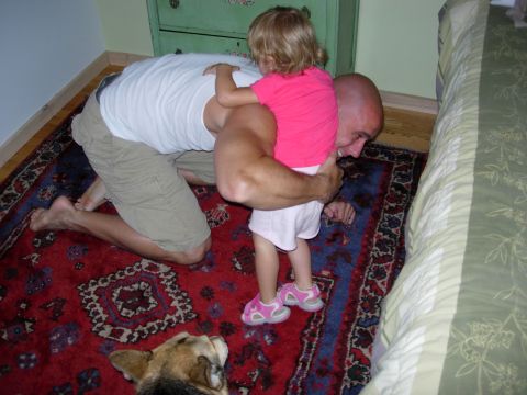 1995 Ford Bronco - Man and child share a hug on a rug, with a dog resting nearby.