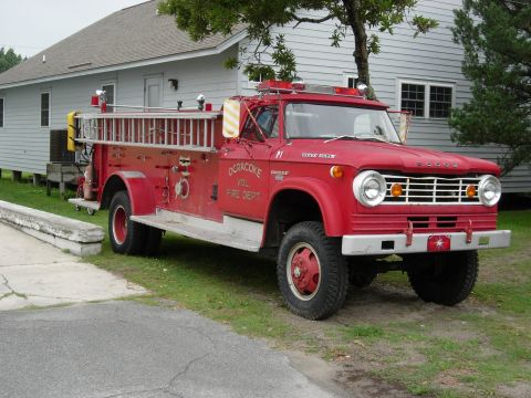 1995 Ford Bronco - A vintage red fire truck is parked in front of a building on a grassy area.