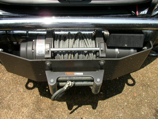 Vehicle front bumper with a winch mounted, showing the cable drum and hook