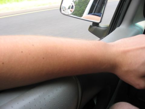 1988 Ford Bronco - View from the driver's seat, showing the arm on the steering wheel and a reflection in the side mirror.