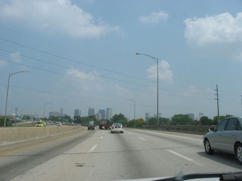 1988 Ford Bronco - Driving on a highway with a distant city skyline under a cloudy sky.