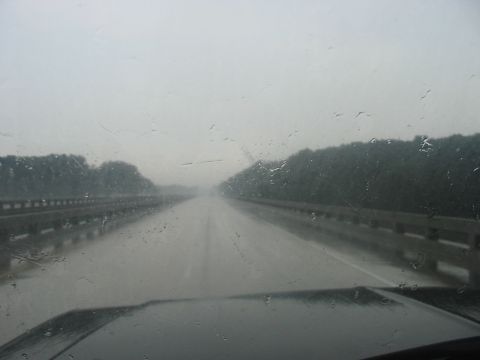 1988 Ford Bronco - Driving on a highway during a rainstorm, with water droplets on the windshield obscuring the view.